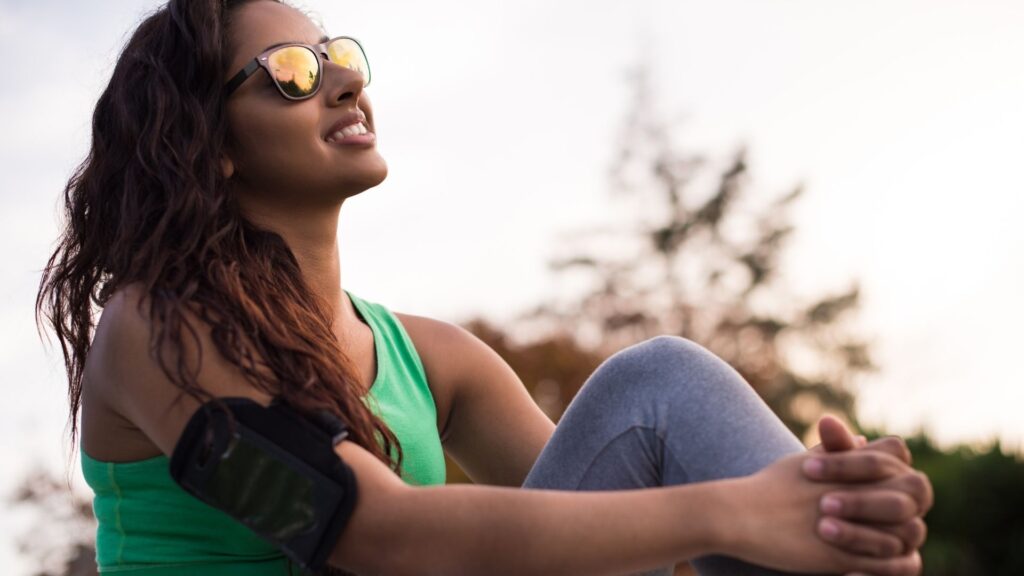 Active woman in sunglasses sitting and looking toward the sky