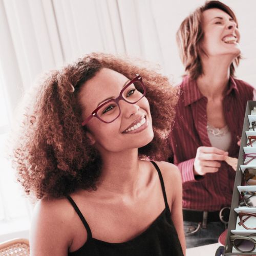 Woman with afro looking up with red glasses on